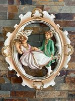 Front view of oval chalkware bas-relief plaque showing courting couple and ornate frame