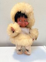 Front view of vintage doll in cream faux-fur parka, pants and boots