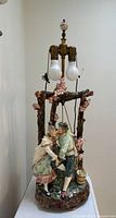 Full view of porcelain figural lamp showing couple, tree arch, brass double socket, missing shade