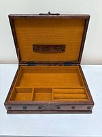 Open box showing mustard fabric interior with compartments and ring rolls