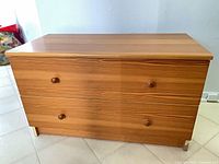 Front view of 2-drawer dresser showing wood grain laminate and round knobs