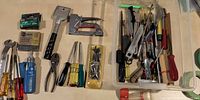 Overview of assorted hand tools on table and in clear bin