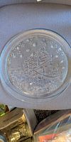 Top view of round clear pressed glass platter showing embossed Christmas tree, stars and gifts design