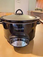Front view of Crock-Pot slow cooker showing brand logo, control panel, lid and handles