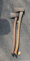 Both axes shown full length on asphalt surface highlighting overall size and handle colors
