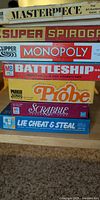 Stacked view of seven vintage board game boxes showing titles and visible wear