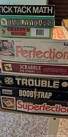 Stack of eight vintage board game boxes showing titles and worn edges
