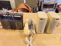 Group view of beige ML 699 desktop speakers, beige corded phone, black portable radio