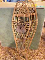 Full view of both wooden snowshoes leaning together