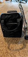Front view of Samsonite carry-on alongside folding luggage cart