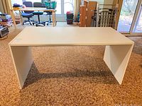 Front view of white laminate desk assembled on carpeted floor