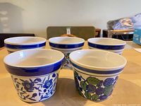 Front view of five blue-and-white ceramic planters showing patterns and rim band