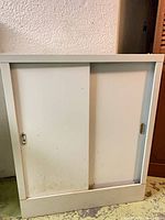 Front view of white metal cabinet with closed sliding doors