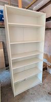 Front view of tall white bookshelf showing all six shelves