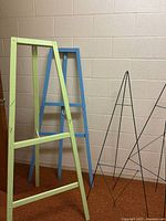 All four easels standing against wall, green wood, blue wood, two black metal