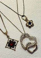 Three necklaces laid out showing pendants and chains