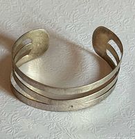 Full view of sterling silver open cuff bracelet showing triple cut-out design