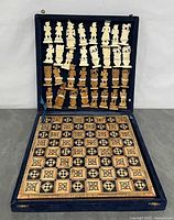 Open case showing 32 carved pieces and inlaid board seated in blue velvet interior