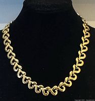 Front view of gold-tone S-link choker necklace on display bust