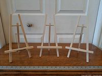 Front view of three wooden tabletop easels on surface