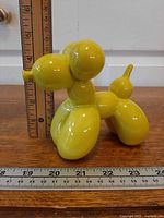 Side view of yellow ceramic balloon dog with rulers showing height and length