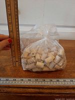 Full bag of wooden spools beside ruler for scale