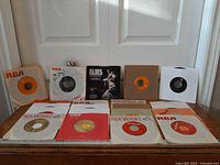 Overall view of 12 RCA Victor 45 RPM records in paper sleeves on tabletop