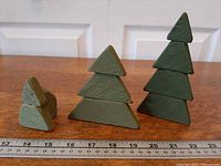 Front view of three green wooden trees with ruler for scale