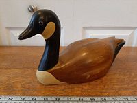 Left side view of full wooden goose decoy with ruler for scale