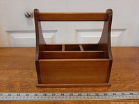Front view of wooden utensil caddy showing rectangular shape, handle, base and ruler for scale
