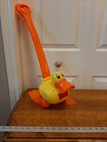 Full view of push toy showing entire handle and duck body next to ruler