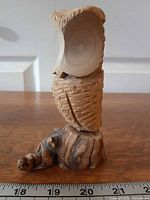 Front view of carved wooden owl on stump base with ruler for scale