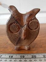 Front view of carved wooden owl with ruler for scale