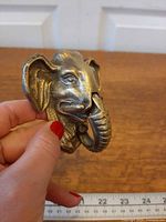 Front angled view of brass elephant head door knocker held in hand