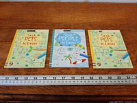 Front view of three Usborne drawing books aligned with ruler for scale
