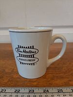 Full side view of mug showing logo and ruler for scale