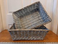 Two grey wicker rattan baskets stacked showing exterior weave and size reference rulers
