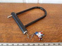 Top view of U-lock and keychain beside ruler showing size