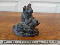 Front view of grey textured two-cub figurine with ruler for scale