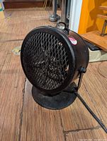 Black industrial floor fan on tilt base, mesh grille visible
