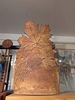 Front view of large studio pottery vase with carved maple leaf relief