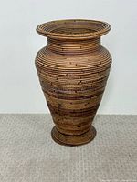 Front view of tall coiled rattan floor vase showing full shape and pattern