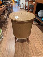 Overall view of oval vinyl hamper on three wooden legs