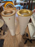 Pair of white acrylic Ikea Fackla floor lamps showing gold tops, segmented columns, cords and foot dimmer switches