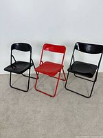 Front view showing all three chairs (two black, one red) unfolded