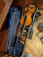 Full-size violin in open blue-lined case with bow and accessories