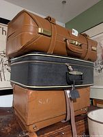 Stacked view of three vintage luggage pieces showing overall condition, materials and sizes