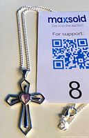Cross pendant on chain beside MaxSold card showing scale