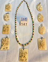 Group shot showing all nine carved bone pendants including the one on beaded necklace