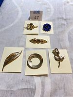 Front view of all five brooches on cards